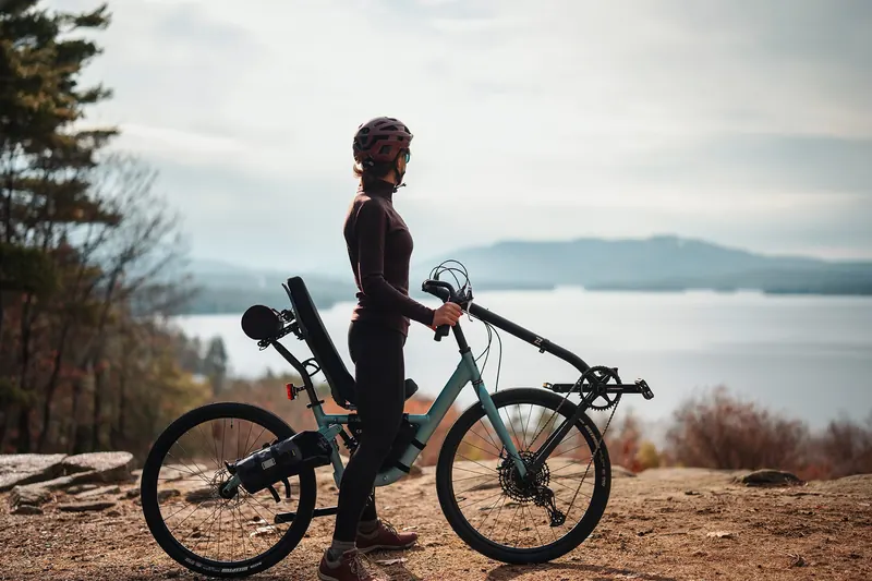 A rider standing beside an Ice Blue Cruzbike A4x on a rocky overlook above a lake