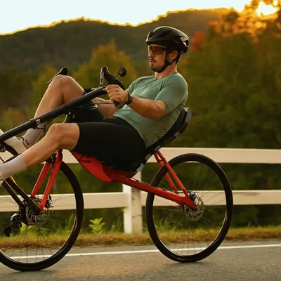A rider on a red Cruzbike on a country road at sunset