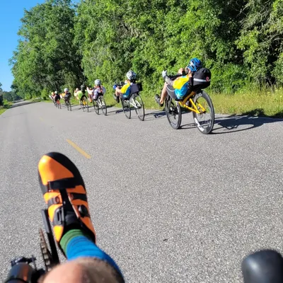 A line of Cruzbike riders on a tree-lined road, seen from the rider at the back