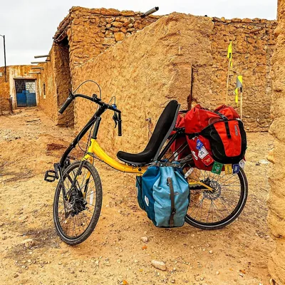 A yellow Cruzbike loaded with panniers in front of an adobe building